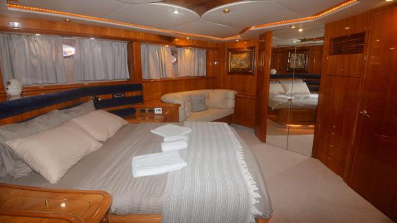 The bedroom on the motor yacht Act features a large and comfortable bed, seating area, and stylish decor.